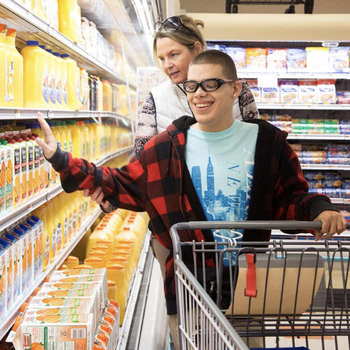 Photo of a young with visual impairment which is assisted by a lady while doing his shopping.